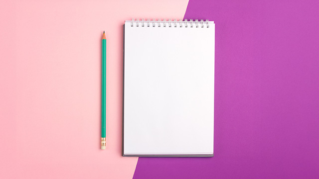 Blank spiral notebook with a green pencil